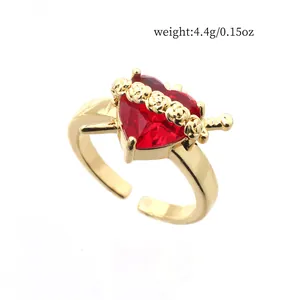 Macro view of gold-tone open ring featuring a red heart zircon and rose detail