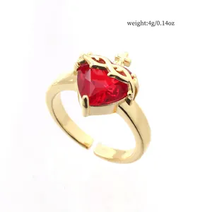 Close-up of golden crown heart ring with red zircon stone and adjustable band detail