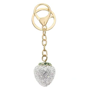 Close-up of a sparkling rhinestone strawberry keychain with gold-colored lobster clasp.
