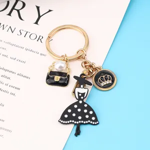Detalle de llavero de moda para mujer con dijes de bolso de perlas y corona de oro