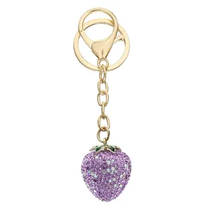Detailed macro view of a purple rhinestone strawberry keychain with gold-toned hardware