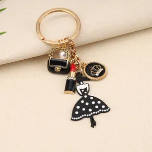Detalle de un llavero de moda con colgantes de pintalabios, bolso y vestido de lunares