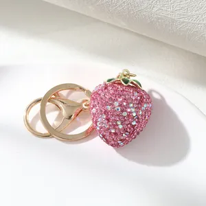 Detailed close-up of pink rhinestone strawberry charm with gold-tone keychain rings