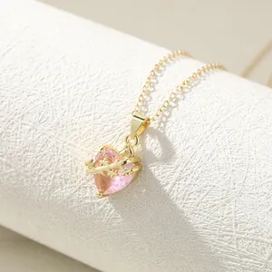 Detailed view of a gold heart necklace with pink crystal and thorny cross motif