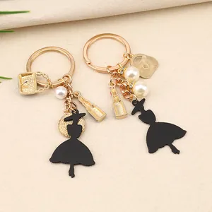 Detalle de llaveros de moda para mujer con dijes de labial dorado, bolso y perlas