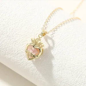 Close-up view of an elegant gold crown heart pendant necklace featuring a pink stone