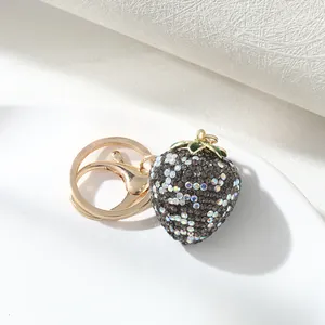 Close-up of a sparkling rhinestone strawberry keychain with gold-toned metal accents.