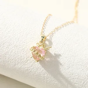Close-up detail of a gold rose thorn heart necklace featuring a pink crystal pendant