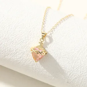 Detailed close-up of a pink heart pendant necklace with gold thorn and cross motifs.