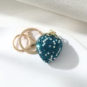 Close-up of a sparkling blue rhinestone strawberry keychain with gold hardware
