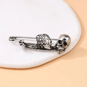 Detailweergave van een vintage zilveren punk schedel en skelet veiligheidsspeld broche