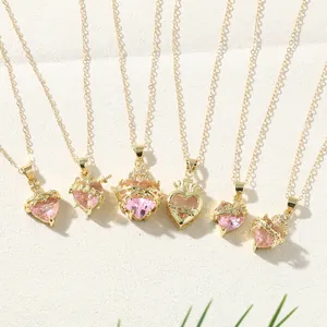 Detail view of pink heart necklaces with crown, thorns, and cross designs in gold finish