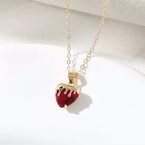 Detailed macro view of an elegant gold-plated melting heart necklace with red crystal.