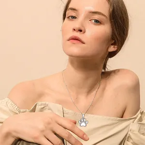 Elegant silver stainless steel paw print cremation urn necklace worn by a model