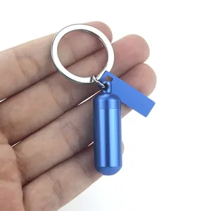 Blue capsule-shaped cremation urn keychain held in hand for size reference.