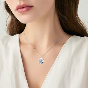 Detailed view of a heart cremation urn necklace with peace dove worn on a model.