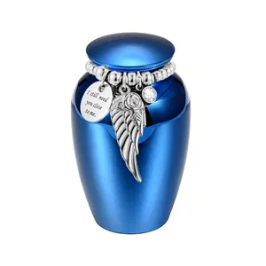 Detailed view of blue cremation urn with silver angel wing and engraved memorial charm.