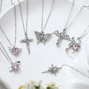 Macro detail of silver alloy necklaces with pink gems in heart and butterfly shapes.
