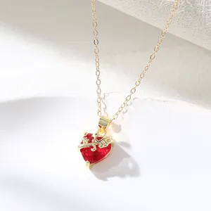 Close-up of elegant gold copper heart necklace with red gemstone and thorn detail