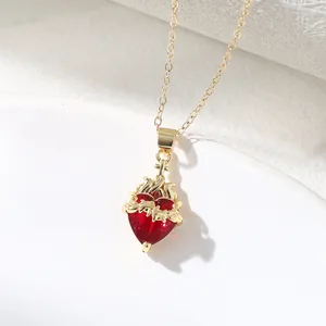 Close-up of golden crown heart pendant with red crystal and thorny cross detail