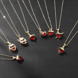 Macro detail view of various gold necklaces with red heart pendants on black background