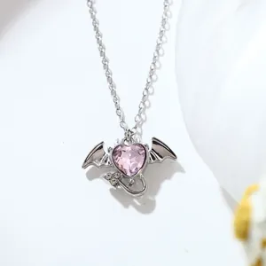 Macro detail of pink heart pendant necklace with silver devil wings and tail design.
