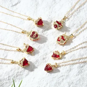 Variety of gold heart pendants with red crystals on textured white stone background