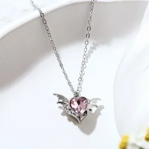 Close-up of pink heart crystal necklace with silver wings on minimalist background