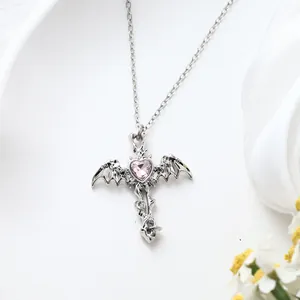 Detailed view of the gothic bat wing cross necklace with a pink heart crystal