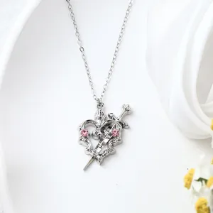 Detailed macro view of a silver alloy heart pendant necklace with pink crystals and sword