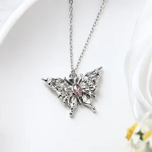 Close-up of a silver butterfly pendant necklace featuring a pink gemstone center.