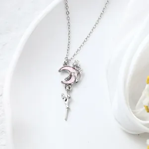 Close-up of a pink crescent moon and crystal-embellished sword pendant necklace.