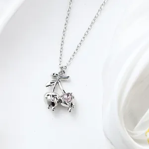 Detailed close-up showing the silver cherry pendant with a sparkling pink heart crystal