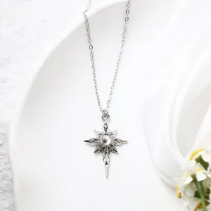 Close-up detail of silver starburst pendant necklace with a light pink gemstone center