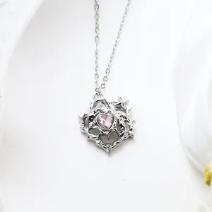 Close-up of silver-toned necklace featuring a pink heart pendant with thorny details.