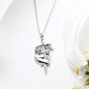 Close-up of silver alloy heart pendant necklace with pink rhinestones and sword detail.