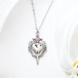 Detail view of silver heart necklace featuring pink rhinestones and sword pendant