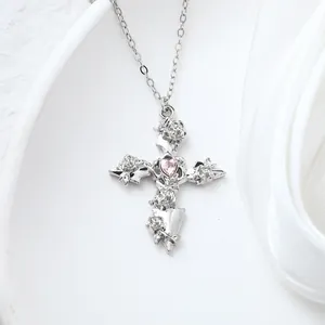 Detailed close-up of silver cross pendant with pink heart stone and rose accents.