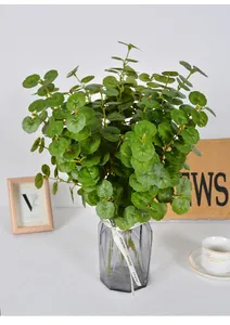 Gedetailleerd overzicht van kunstmatige groene planten in een grijze glazen vaas.