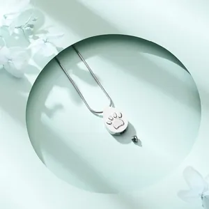 Close-up detail of silver stainless steel teardrop urn necklace with pet paw print design