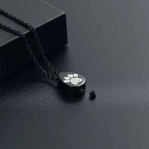 Detail view of black stainless steel teardrop urn necklace with rhinestone paw print design