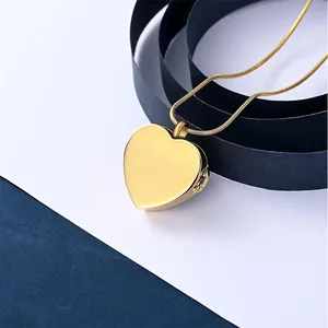 Macro view of a gold heart-shaped cremation locket pendant with snake chain