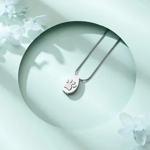 Macro view of teardrop stainless steel cremation necklace featuring a paw print design.