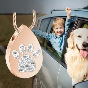Rose gold teardrop urn pendant with crystal paw print and dog in background