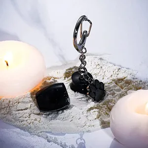Close-up of black pet cremation urn keychain with paw charm and opened vial lid
