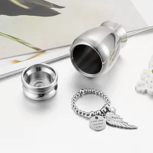 Detailed view of polished silver pet urn with engraved angel wing keychain accessory.