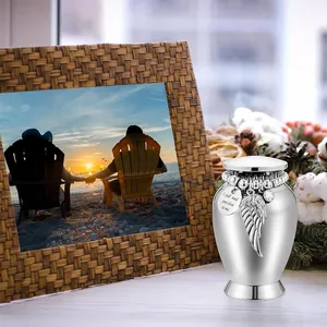 Polished silver memorial urn featuring angel wing charm and engraved heart pendant
