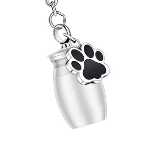 Close-up detail of a silver pet cremation urn keychain with black paw print charm