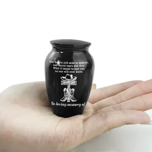 Kleine schwarze Urne mit Cowboy-Gravur, zur Größenbestimmung in der Hand gehalten