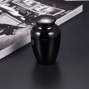 Close-up of a small black memorial cremation urn for pet ashes on a dark table